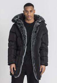 Sort puffet jakke med en faux fur hætte og for, med lynlås og trykknaplukning, sidelommer og en let løs pasform.