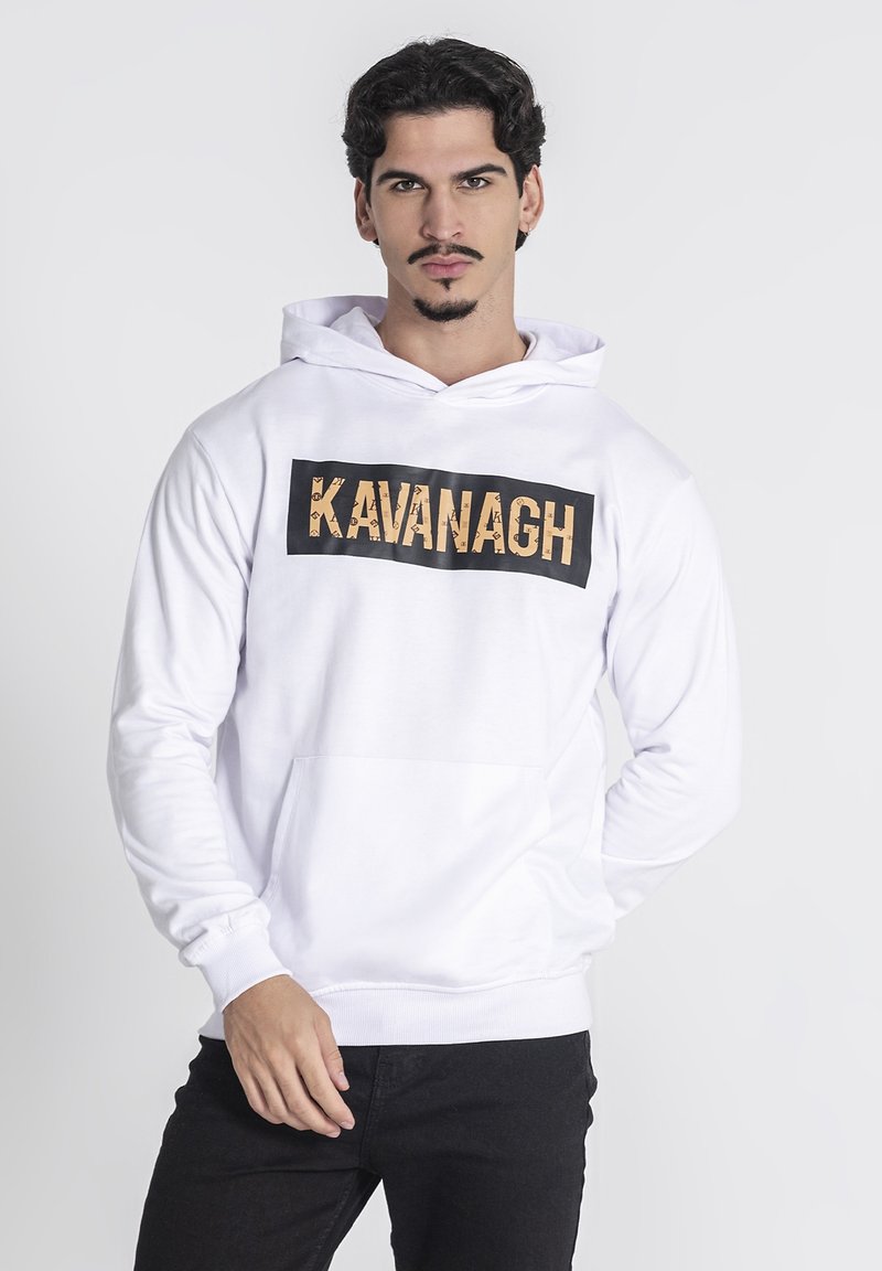 Biely mikina s kapucňou, na prednej strane s veľkým čiernym obdĺžnikom, na ktorom je napísané slovo "KAVANAGH" textúrovaným zlatým písmom. Na prednej strane je klokaní vrecko.