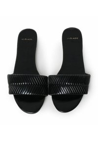 Sandales noires à glissière avec une sangle texturée et rainurée. Semelle intérieure et semelle lisses, arborant le logo de la marque en doré sur la semelle intérieure.