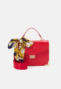 Rød faux krokodille taske med et struktureret design, har en guldfarvet lås, et stofsjal som accent og en aftagelig skulderrem.