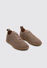 Baskets perforées marron avec un bout arrondi, une surface texturée, un design à lacets élastiques et une semelle en caoutchouc avec des accents cousus.