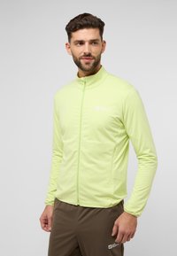 Hellgrüne Sportjacke mit hohem Kragen, Reißverschluss und mit Reißverschluss versehenen Taschen. Glatte Textur mit einem Logo auf der Brust.