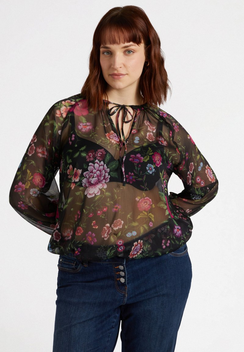Bluză neagră transparentă cu modele florale în nuanțe de roz, violet și albastru. Are un guler legat și mâneci lungi; material ușor.