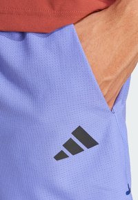 Heledad heledad tumepunaste prikka, millel on tekstuuriga pind, musta Adidas logo küljes ja küljetasku.
