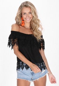 Juoda off-the-shoulder maikutė su nėriniu ir taškelių tekstūra, derinama su suplėšytais džinsiniais šortais. Oranžinės gėlėtos auskarai užbaigia įvaizdį.