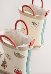 Zwei cremefarbene Behälter mit roten Griffen und türkisfarbenen Akzenten, verziert mit festlichen Aufklebern und einem flauschigen weißen Innenfutter.