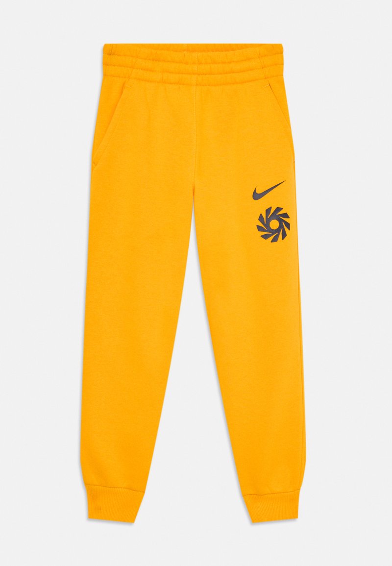 Dzelteni flīsa sporta bikses ar elastīgu jostasvietu un aprocēm, sānu kabatām, un melno Nike svītru un grafisko logotipu kreisajā augšstilbā.