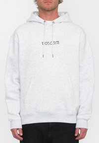 Sweat à capuche gris en tissu doux, avec une poche kangourou à l'avant et des cordons de serrage. Texte logo noir sur la poitrine. Poignets et ourlet côtelés.