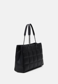 Black quilted tote bag with two flat handles and chain accents. Made of smooth material, featuring a rectangular shape and minimalist design.