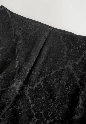 Schwarzer Rock mit einem strukturierten Blumenmuster, aus einem glatten Material gefertigt. Mit einem hinten eingearbeiteten Faltenwurf für ein gestalterisches Detail.
