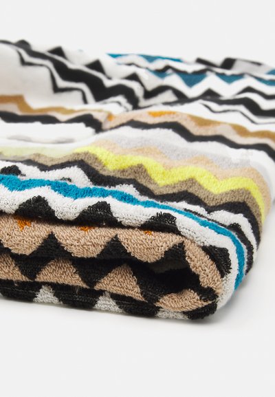 Asciugamano multicolore con un motivo a zig zag in nero, bianco, marrone, blu, arancione, giallo e verde su un morbido e assorbente tessuto di spugna.