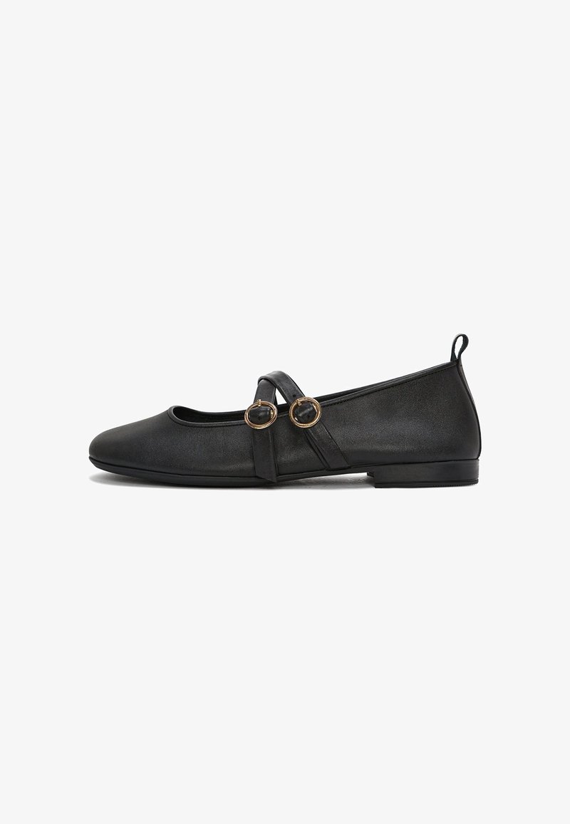 Ballerines en cuir noir avec un bout rond, une semelle plate et des doubles brides avec des accents circulaires en ton doré. Texture lisse.