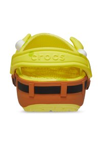 Zoccoli giallo brillante con soletta testurizzata e cinturino flessibile. Presentano occhi giocosi e una base arancione con accenti neri.