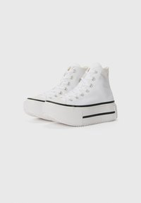 High-top sneakers made of white canvas with silver eyelets, a black stripe on the sole, and a textured rubber outsole.