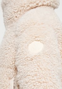 Lichtbeige fleecejack met een gestructureerd, pluizig oppervlak. Voorzien van een ronde, witte "Save the Duck"-logo op de mouw.