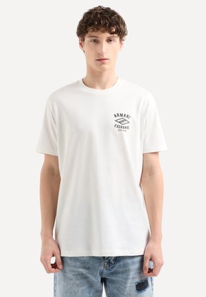 T-shirt bianco in cotone con un piccolo logo nero "Armani Exchange" sul lato sinistro del petto. Maniche corte e scollatura tonda.