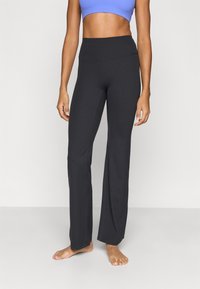 Μαύροι παντελόνες γιόγκα φτιαγμένοι από ελαστικό ύφασμα, με ψηλή μέση και ίσια γραμμή στα πόδια. Λείο υλικό χωρίς ορατά μοτίβα.