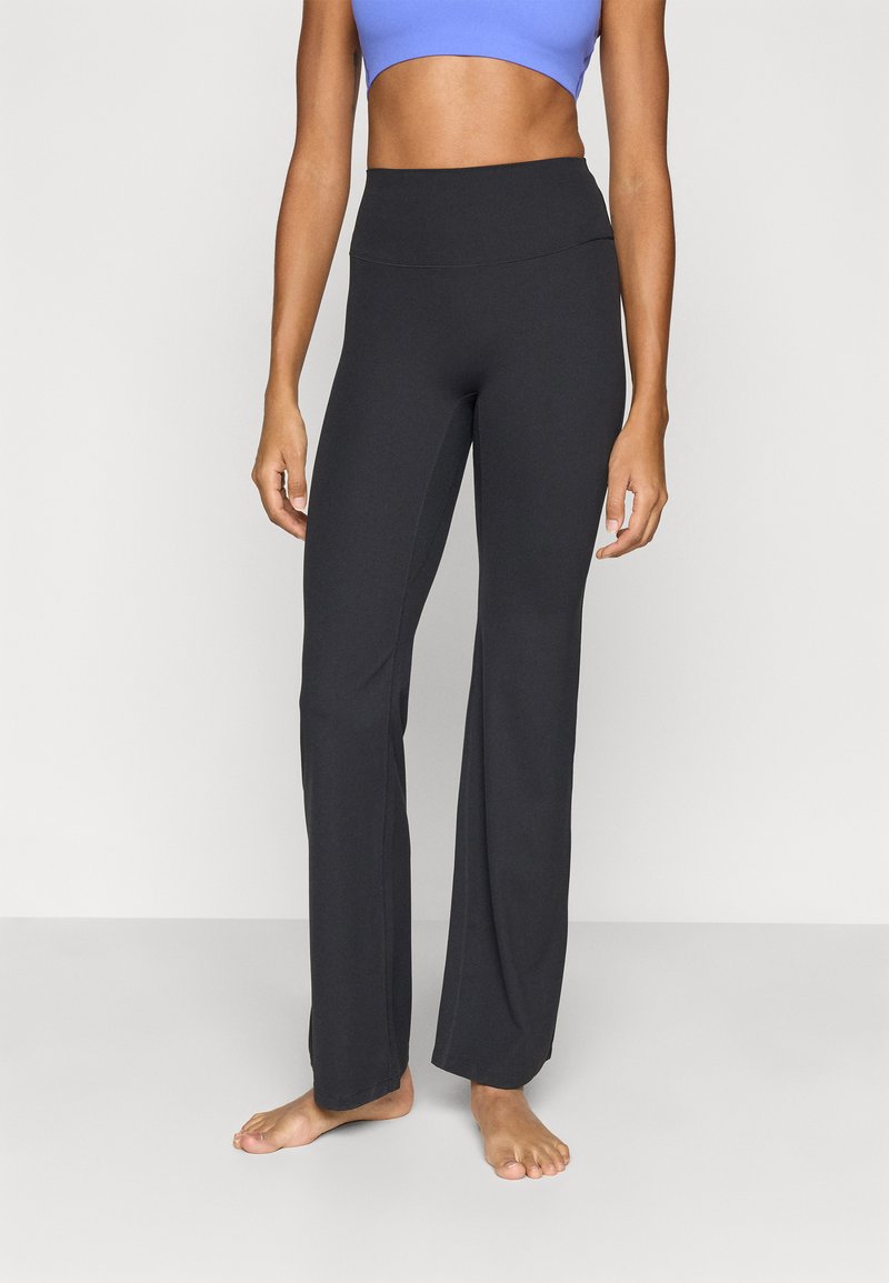 Μαύροι παντελόνες γιόγκα φτιαγμένοι από ελαστικό ύφασμα, με ψηλή μέση και ίσια γραμμή στα πόδια. Λείο υλικό χωρίς ορατά μοτίβα.