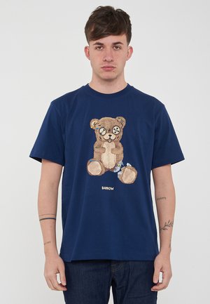 T-shirt in cotone blu navy con grafica di un orsetto con dettagli cuciti e bottoni per gli occhi. Logo discreto in basso.