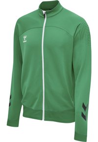 Zielona sportowa kurtka na pełny zamek z białym suwakiem, czarnymi wzorami w kształcie jodełki na rękawach oraz małym logo na lewej piersi.