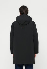 Zwarte jas met een capuchon, met een lange ontwerp, gladde textuur en een horizontale accent in rood, wit en blauw op de bovenrug.