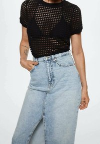 Mustat verkosta neulotut yshort-sleeve-paitat, yhdistettyinä vaaleansiniseen korkeavyötäröiseen farkkuhameeseen, jossa on etuleikkaus ja risat helmat.