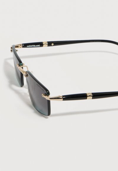 Μαύρα και χρυσά χωρίς περίγραμμα γυαλιά ηλίου Montblanc με σκούρους ορθογώνιους φακούς και λεπτά μπράτσα σε λευκό φόντο.