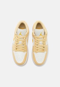 Gula och vita sneakers med perforerat tår, mesh-tunga och platta snören. Har en liten logotyp och texturerade läderdetaljer.