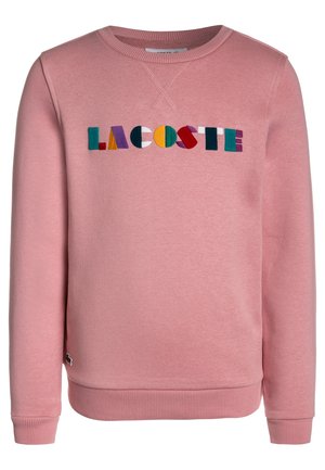 Vaaleanpunainen collegepaita, jossa on resorikaulukset ja -helma, edessä monivärinen kirjailtu "LACOSTE"-logo. Valmistettu pehmeästä materiaalista.