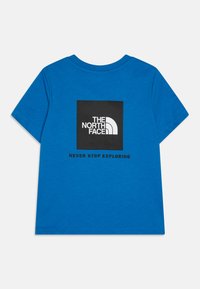 Mėlynas medvilninis marškinėlis su juodu kvadratiniu logotipu, ant kurio yra užrašas "THE NORTH FACE" ir "NEVER STOP EXPLORING" nugarinėje pusėje. Trumpomis rankovėmis.