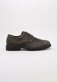 Zapato de vestir para hombre en ante marrón oscuro, con cordones, suela de goma negra y tacón bajo, mostrado de perfil sobre un fondo claro.
