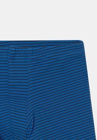 Blå stripete leggings med en blanding av mørk og lys blå horisontale linjer, laget av et mykt, elastisk materiale. Uten lommer.