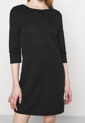 Abito nero con una texture trapuntata, maniche a tre quarti e scollatura rotonda, caratterizzato da una vestibilità ampia. Materiale morbido, design minimalista.