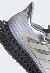 Scarpa sportiva grigia e lavanda con tomaia in mesh testurizzato, sovrapposizioni sintetiche e una distintiva suola intermedia nera a rete.