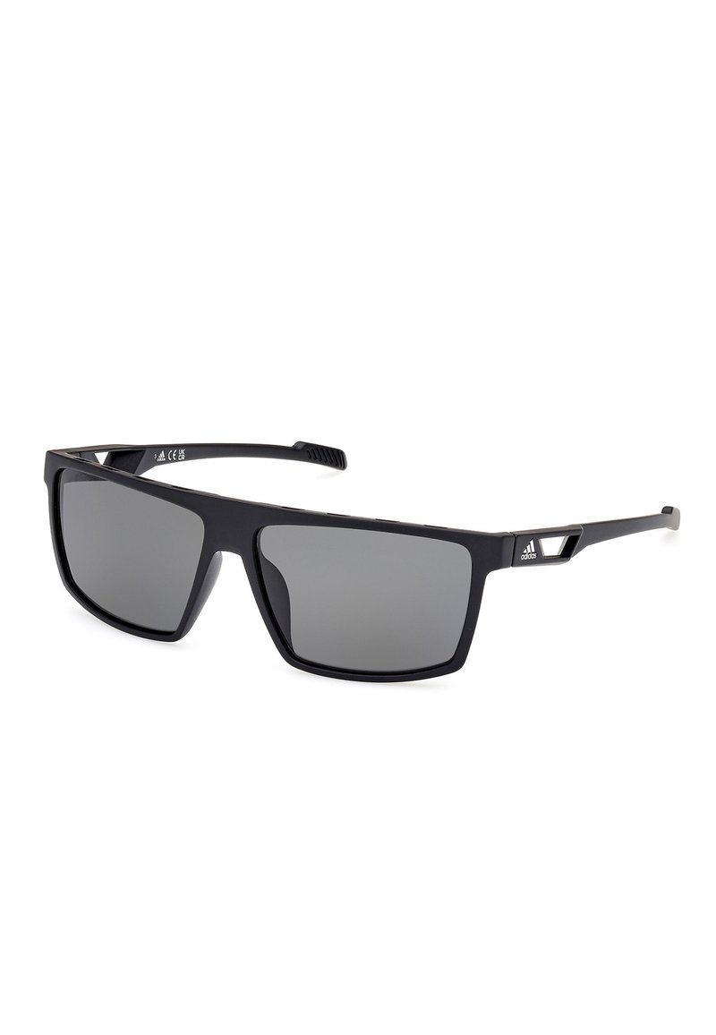 Černé sluneční brýle se čtvercovými skly, šedými tónovanými skly, matným povrchem, texturovanými stranami a výraznými trojúhelníkovými akcenty na rámu.