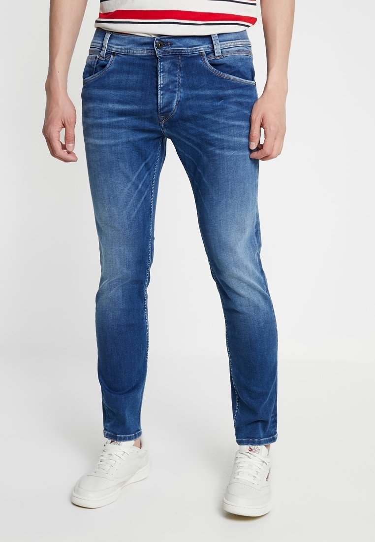 Blå denimjeans med slim pasform, der har en lys vask, diskrete whiskering-detaljer, fem lommer og lynlås foran. Sammen med hvide sneakers.