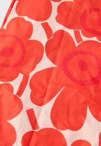 Raudona gėlių audinio su didelėmis, persidengiančiomis gėlėmis ant šviesiai rožinės fono, su apvaliais žiedų centrais ir stilizuotais stiebais įvairių formų.