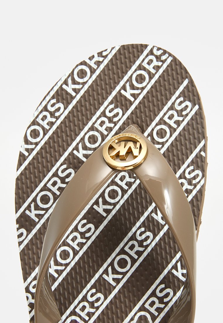 Braune Flip-Flop-Sandale mit glänzenden Riemen, die ein kreisförmiges goldenes Logo und eine strukturierte Fußbett mit wiederholtem weißen "KORS"-Branding aufweist.