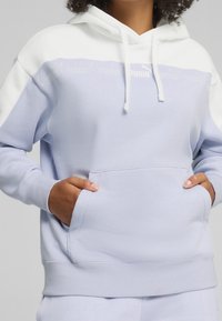 Lichtblauwe hoodie met witte accenten. Voorzien van een kangoeroezak, trekkoorden en een gedrukt logo op de borst. Gemaakt van zachte stof.