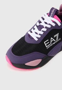 Lilla og svart trening sneakers med mesh-overdel, hvite snøringer og rosa detaljer. Inkluderer logo og teksturert såle.
