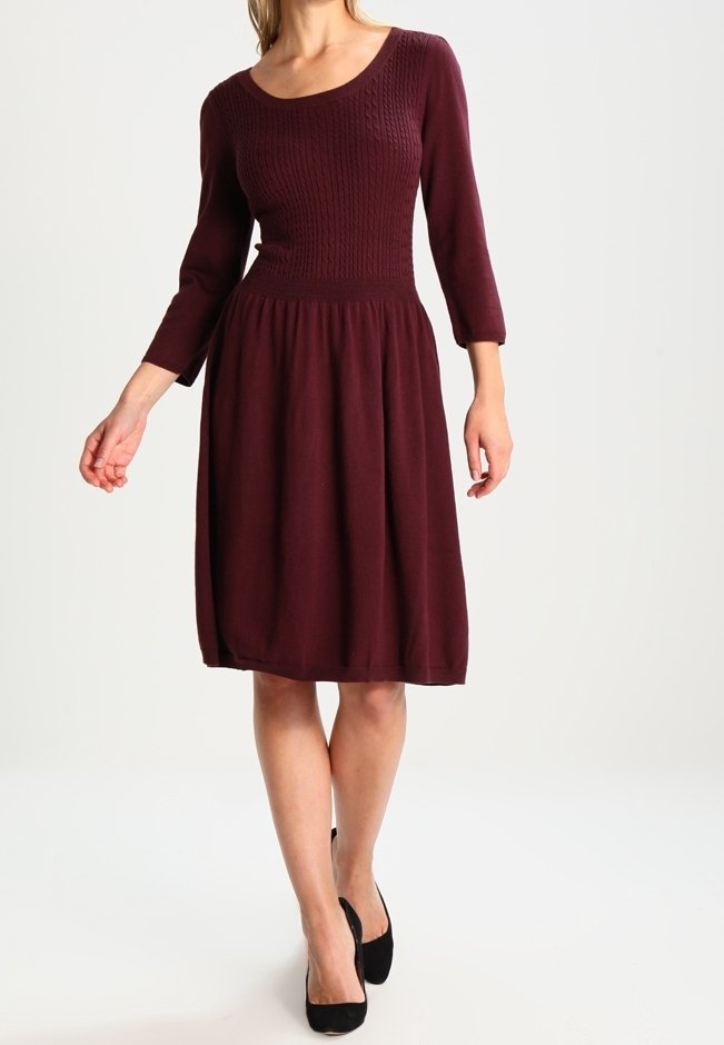 Robe bordeaux avec un haut en tricot présentant un décolleté en U et des manches trois quarts, jupe en tissu fluide et détails plissés à la taille.