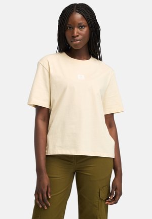 T-shirt beige à manches courtes en coton avec un logo carré sur la poitrine. Le t-shirt présente une coupe décontractée et une texture lisse.