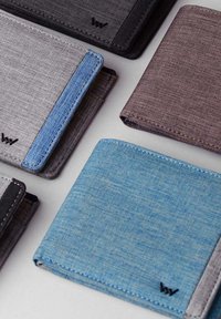 Multi-colored wallets featuring fabric material, with gray, blue, and brown tones, and varying stitching details. Compact rectangular shape.