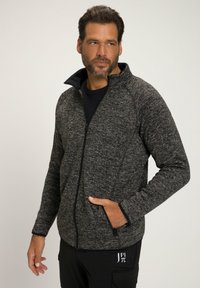 Chaqueta gris oscuro con un tejido texturizado, cuello alto y cierre de cremallera. Presenta bolsillos laterales y detalles en negro en los puños y el dobladillo.
