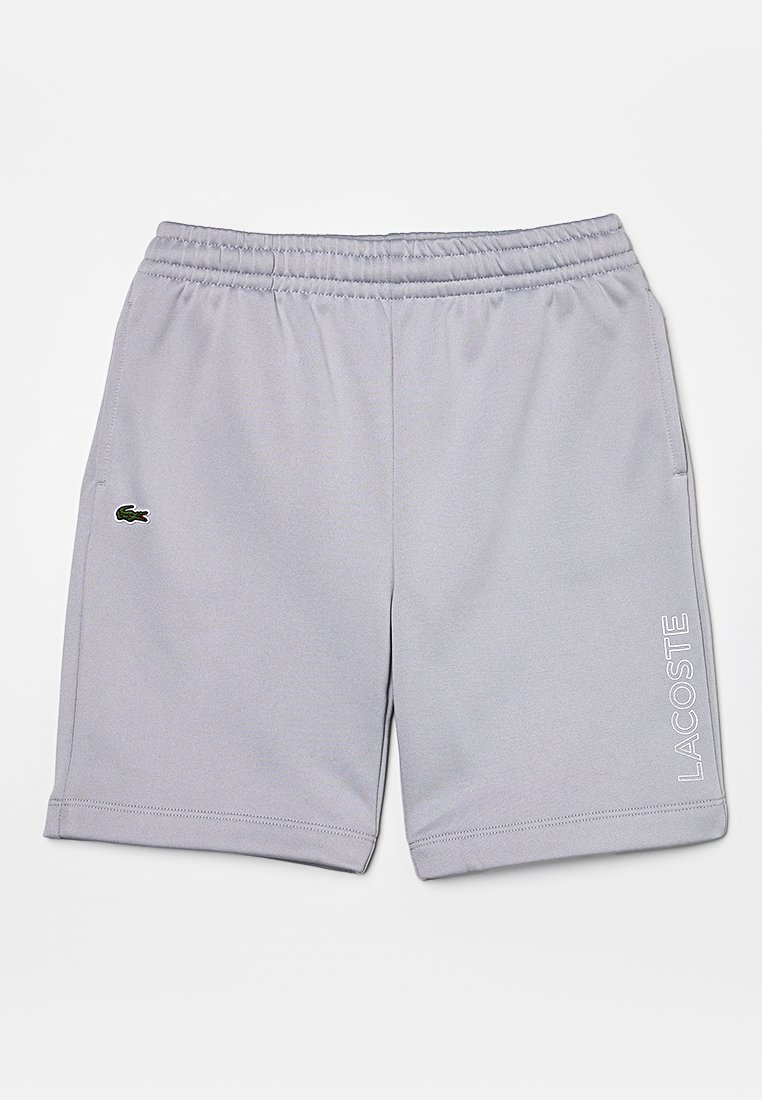Shorts gris clair avec une ceinture élastique, arborant un logo Lacoste vert et le texte blanc "LACOSTE" sur le côté. Texture douce et lisse.