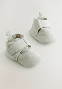 Grå tyg babystövlar med en mjuk, texturerad yta, med ett överlappande Velcro-band och en liten dragflik för enkel påtagning.