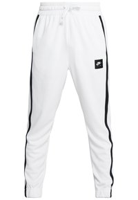 Vita joggingbyxor med svarta sidostreck, elastisk midja och en liten svart Nike Air-logotyp på vänster lår. Slät tygtextur.