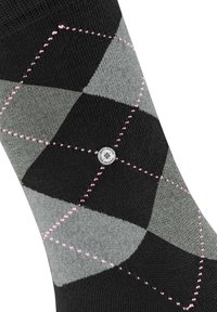 Calcetín de patrón argyle en negro y gris con acentos de costura en rosa, que presenta un logo circular en el lateral. Fabricado en tejido de punto.