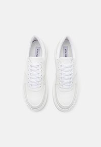 Zapatillas de cuero blanco con cordones planos, punteras redondeadas y detalles cosidos. Textura suave y diseño minimalista, con una plantilla de marca.