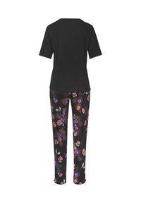 Camiseta negra de manga corta combinada con pantalones de estampado floral en negro, con acentos en púrpura, rosa y verde. Textura de tela suave.